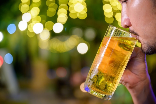 Primer plano de joven bebiendo cerveza alegremente Levantando un vaso de cerveza en el pub para celebrar el éxito del trabajo autónomo.