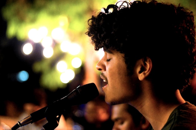 Primer plano de un joven cantando en un concierto