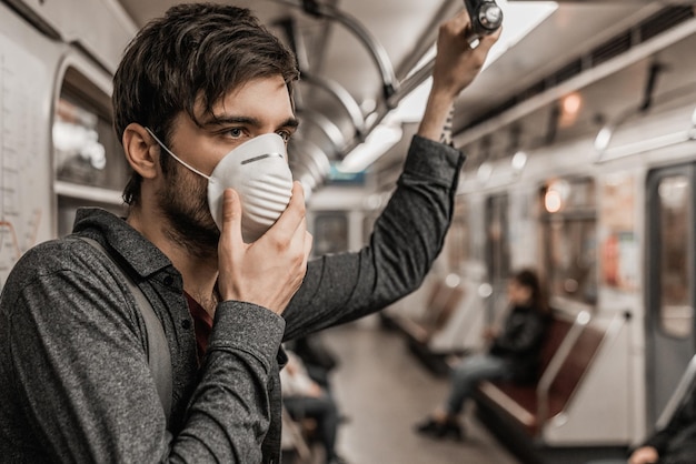 Primer plano de un joven caucásico con mascarilla protectora en el tren subterráneo