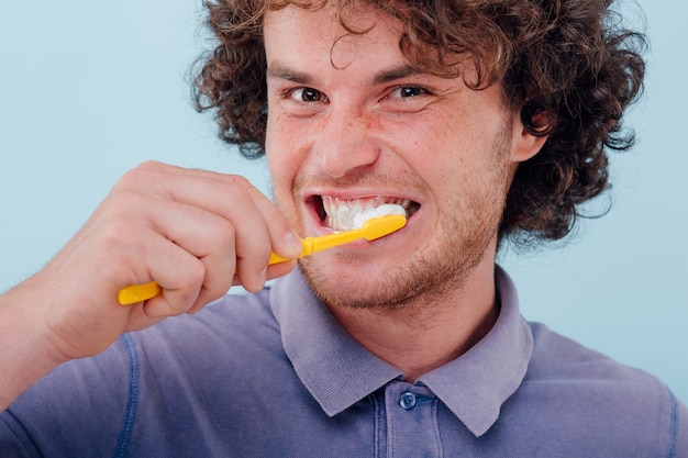 Primer plano, joven cepillarse los dientes con cepillo y pegar.