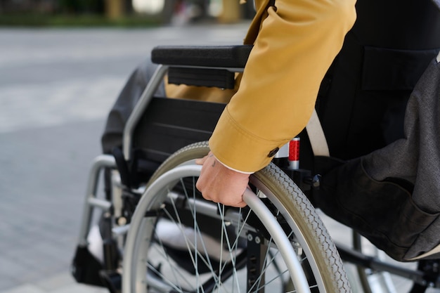 Primer plano de un joven con discapacidad moviéndose en silla de ruedas por la calle