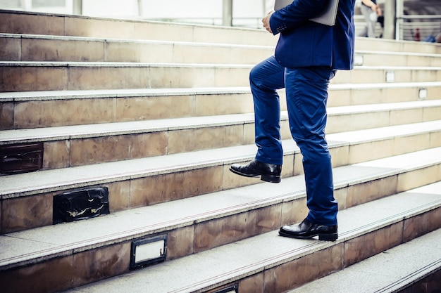 Foto un primer plano de un joven empresario caminando por las escaleras fuera de la oficina.