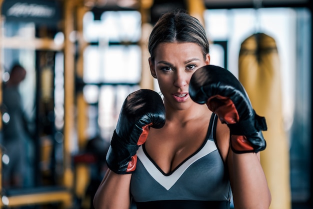 Primer plano de una joven en forma de guantes de boxeo, vista frontal.