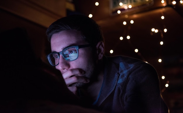 Primer plano de un joven con gafas en el cuarto oscuro