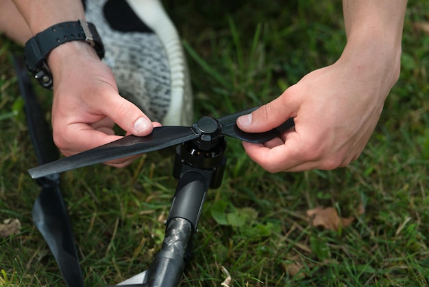 Primer plano de un joven ingeniero que aprieta la hélice de un dron Uav con una herramienta manual en el parque