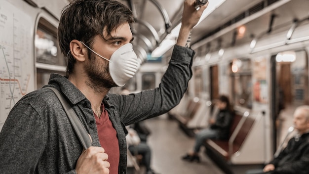 Primer plano de un joven con mascarilla protectora en el tren subterráneo para prevenir infecciones