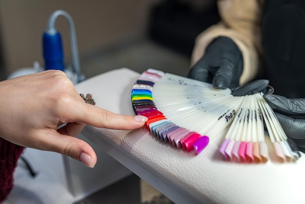 Primer plano de una joven morena tratando de elegir el color correcto de esmalte de uñas en un salón de belleza Concepto de trabajo de salón de belleza para mujeres