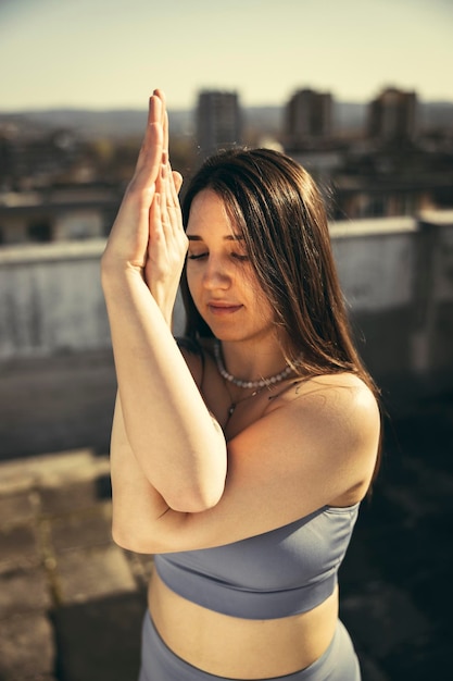 Primer plano de una joven mujer relajada practicando yoga en una terraza en la azotea.