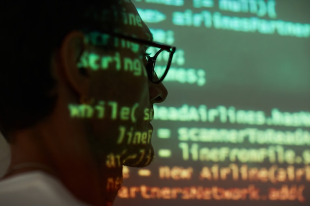 Foto primer plano de joven programador en anteojos visitando presentación de computadora y estudiando tecnologías informáticas