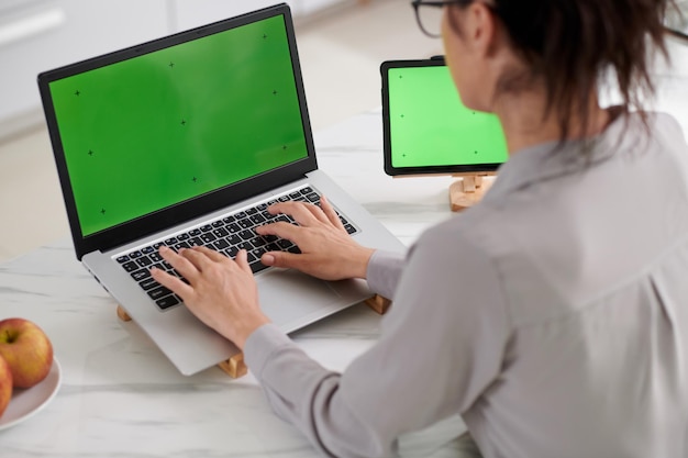 Primer plano de una joven programadora sentada frente a una laptop con pantalla verde