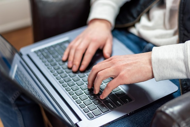 Primer plano de un joven usando una laptop en casa