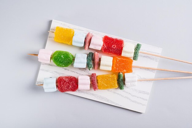 Un primer plano de los kebabs de caramelos de goma en pinzas servidos en la mesa