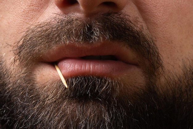 Foto primer plano de labios enojados cara barbuda de hombre con palillo en los dientes emociones enojadas de peligro de bandido un...