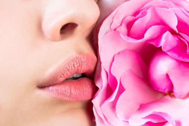 Primer plano de labios femeninos con flor rosa Primer plano sexy labio femenino Lápiz labial de color rojo Labios de mujer