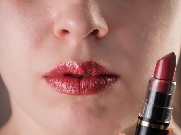 Primer plano de labios femeninos regordetes Los labios están pintados con lápiz labial burdeos brillante