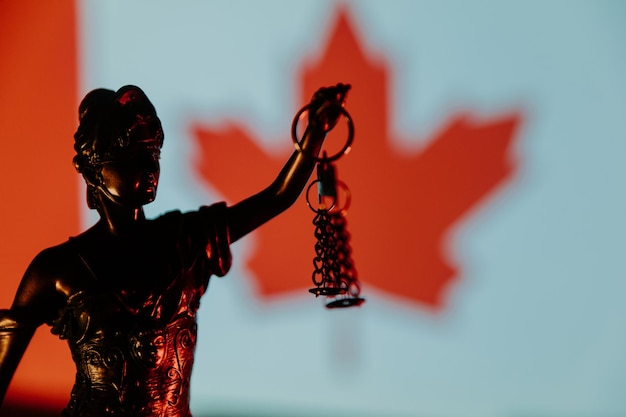 Primer plano de Lady Justice y bandera de Canadá en el fondo