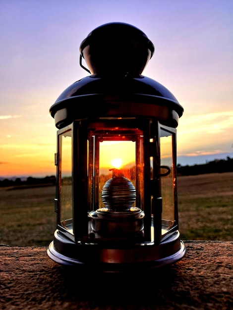 Foto primer plano de una lámpara iluminada en el campo contra el cielo durante la puesta de sol