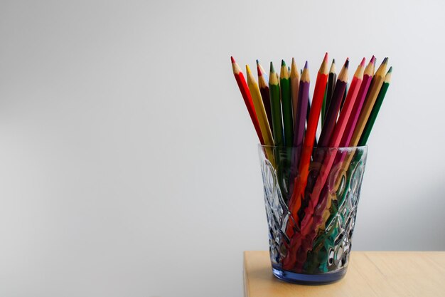 Primer plano de lápices de color en vidrio sobre un fondo blanco