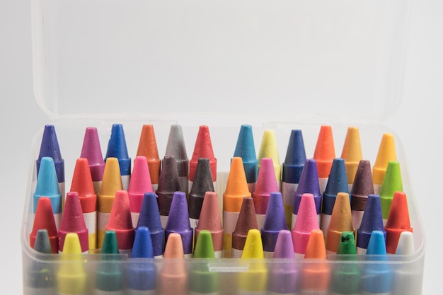 Primer plano de lápices de colores en un recipiente de plástico contra un fondo blanco