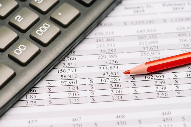 Foto primer plano de lápiz de color rojo con calculadora sobre el informe financiero