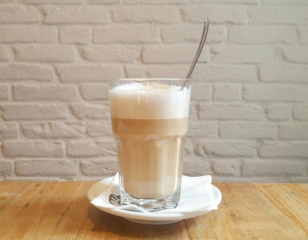 Primer plano de latte macchiato en la mesa contra la pared