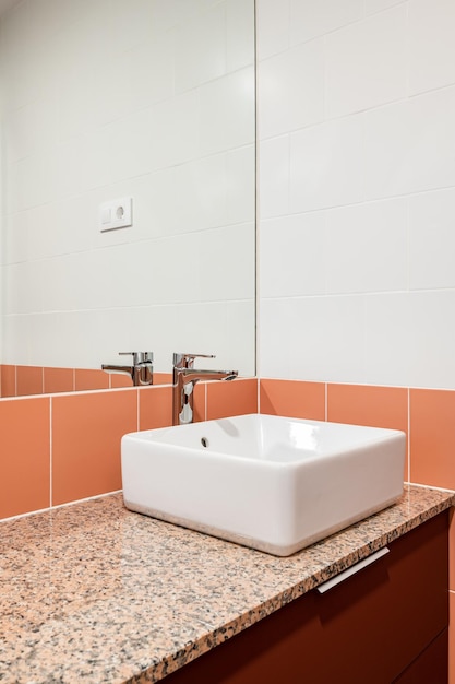 Primer plano de lavabo con espejo y azulejos rojos en un nuevo y elegante cuarto de baño después del concepto de renovación de un