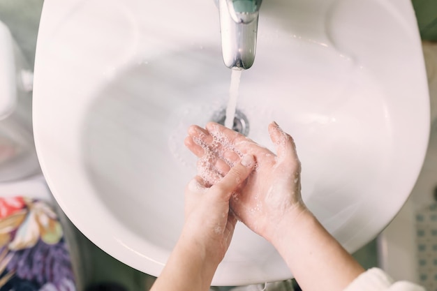 Primer plano de lavarse las manos con jabón sobre el lavabo del baño