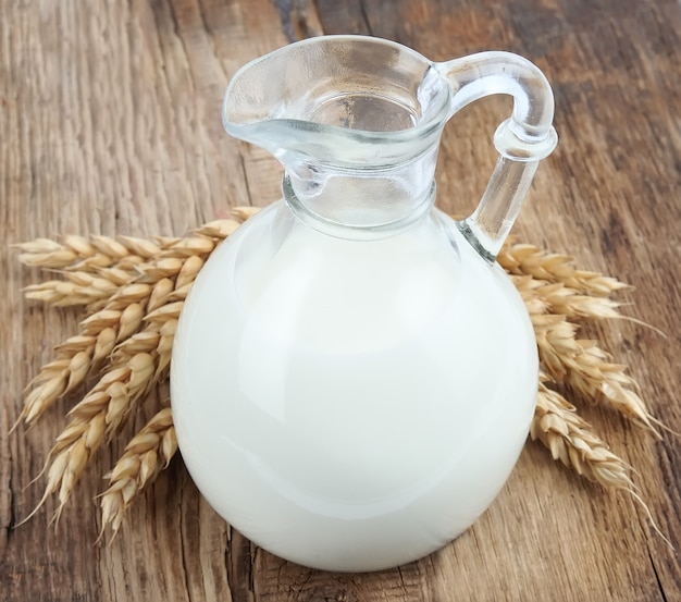 Primer plano de leche y trigo en mesas de madera