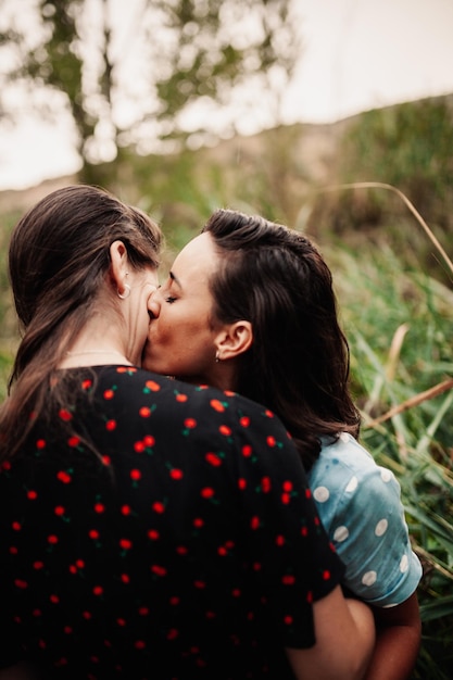 Foto primer plano de lesbianas besándose en el bosque.