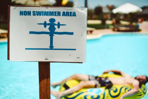 Primer plano de un letrero de información frente a la piscina
