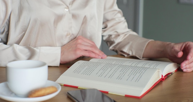 Primer plano de un libro de lectura femenino y tomando café en la mesa en casa Pasatiempo de tiempo libre y concepto de pasatiempo en el hogar