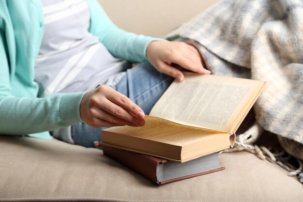 Primer plano del libro de lectura de la mujer joven en el fondo interior del hogar