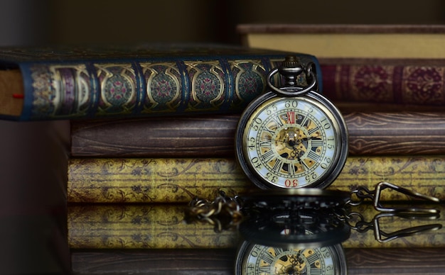 Primer plano de libros viejos y reloj de bolsillo vintage en la mesa