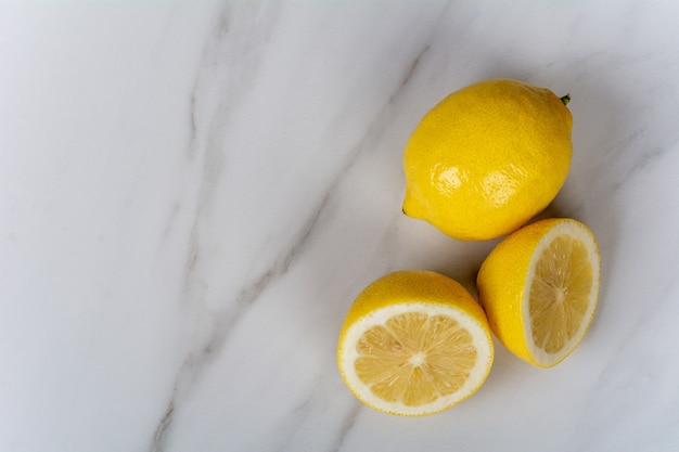 Primer plano de limones y rodajas de limón en la mesa de mármol. Concepto de cocina y comida.