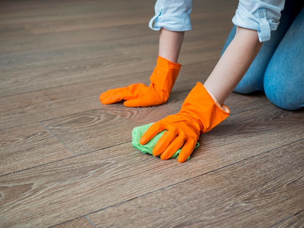 Primer plano limpiando el piso con guantes de goma