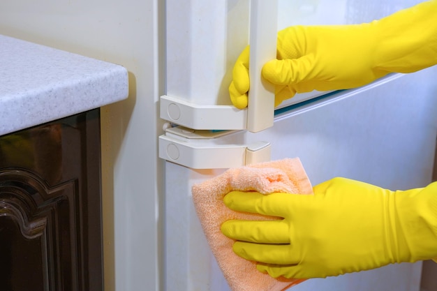 Primer plano de limpieza de la casa de manos enguantadas frotando el polvo en la cocina