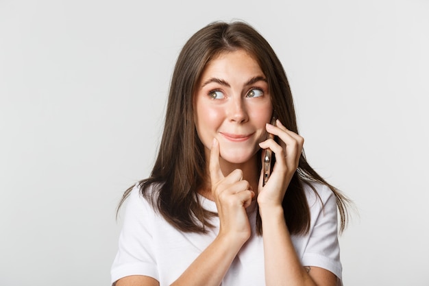 Primer plano de linda chica intrigada hablando por teléfono, mirando interesado.