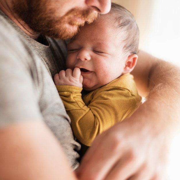 Foto primer plano lindo bebé siendo abrazado por el padre