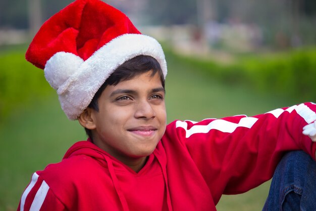 Foto primer plano de un lindo niño con camiseta roja gorra de santa sonriendo felizmente
