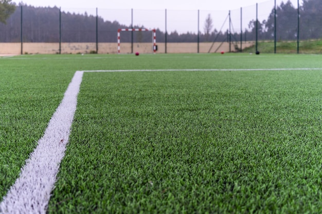 Primer plano de la línea blanca de un campo de fútbol que apunta a la meta del oponente y una pelota de fútbol