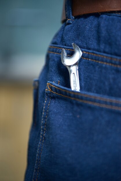 Primer plano de una llave ajustable en el bolsillo trasero de los pantalones vaqueros del hombre