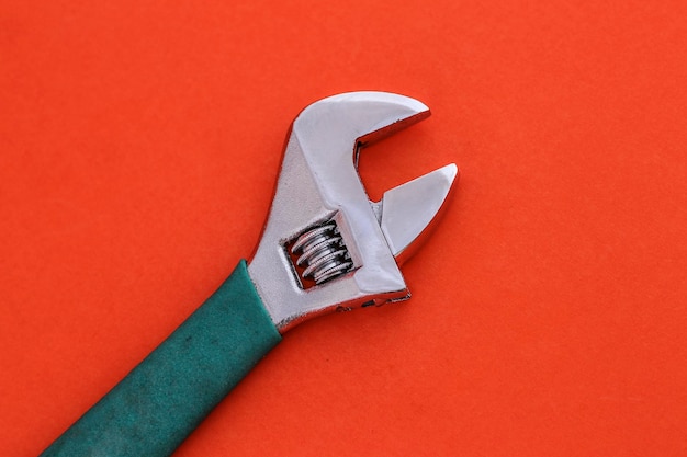 Foto primer plano de una llave ajustable contra un fondo naranja