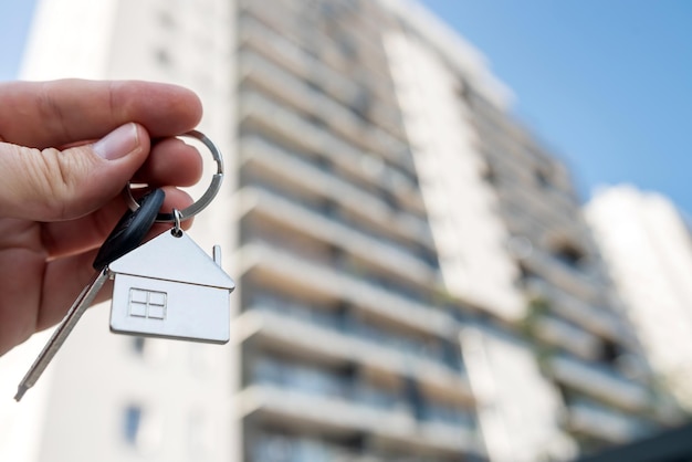 En primer plano la llave de la casa en la mano de la mujer contra el nuevo apartamento Concepto de nueva casa inmobiliaria