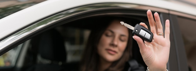 Primer plano de las llaves del coche nuevo en manos de una mujer joven Comprador feliz