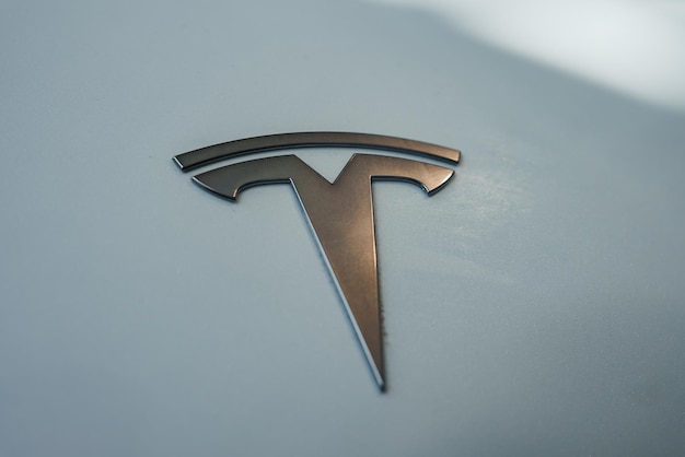Primer plano del logotipo de Tesla en superficie metálica con fondo gris claro