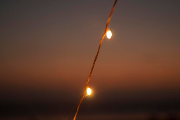 Foto primer plano de las luces iluminadas contra el cielo durante la puesta de sol