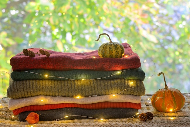 Primer plano de luces iluminadas en ropa cálida y calabazas y piñones sobre la mesa