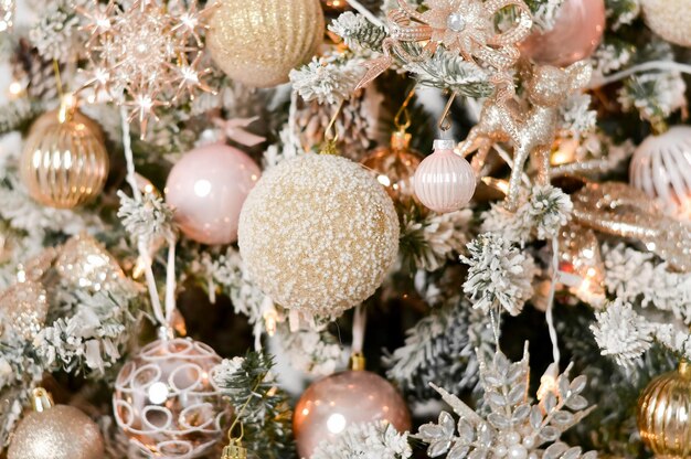 Primer plano del lujoso árbol de Navidad con bolas de plata blanca y rosa, nieve y guirnaldas brillantes