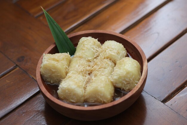 un primer plano de lupis con coco rallado y salsa de azúcar marrón servido en un cuenco de madera concepto de foto de comida tradicional indonesia