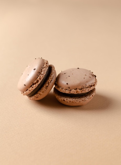 Primer plano de macarrones franceses de chocolate o macarrones de galletas de almendra en un espacio de copia de fondo beige